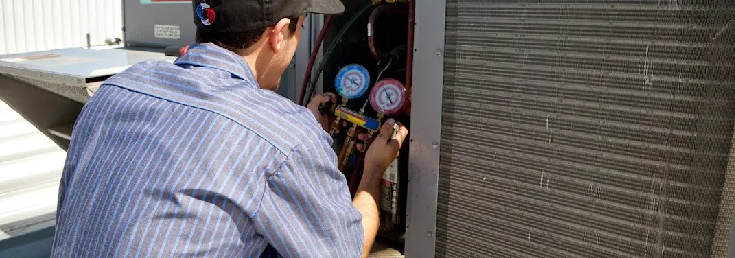 HVAC technician servicing a condenser unit in Highland Park